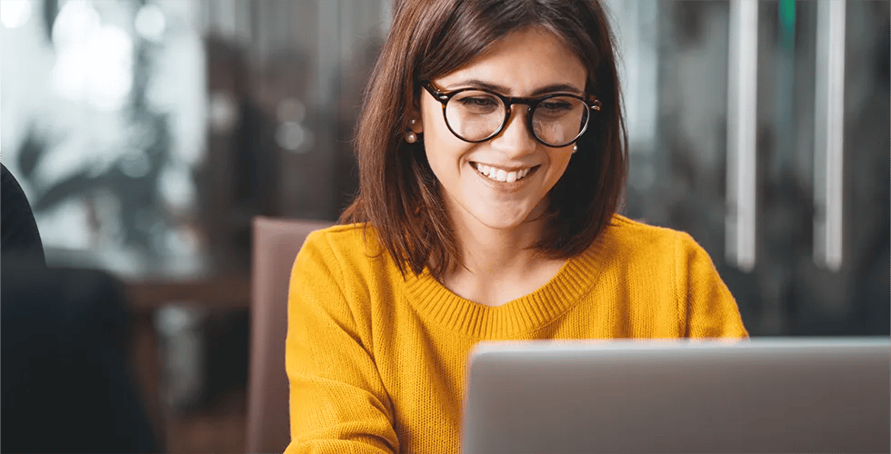 Eine junge Frau schaut auf einen Laptop und freut sich über die Übersetzung ihrer Webseite