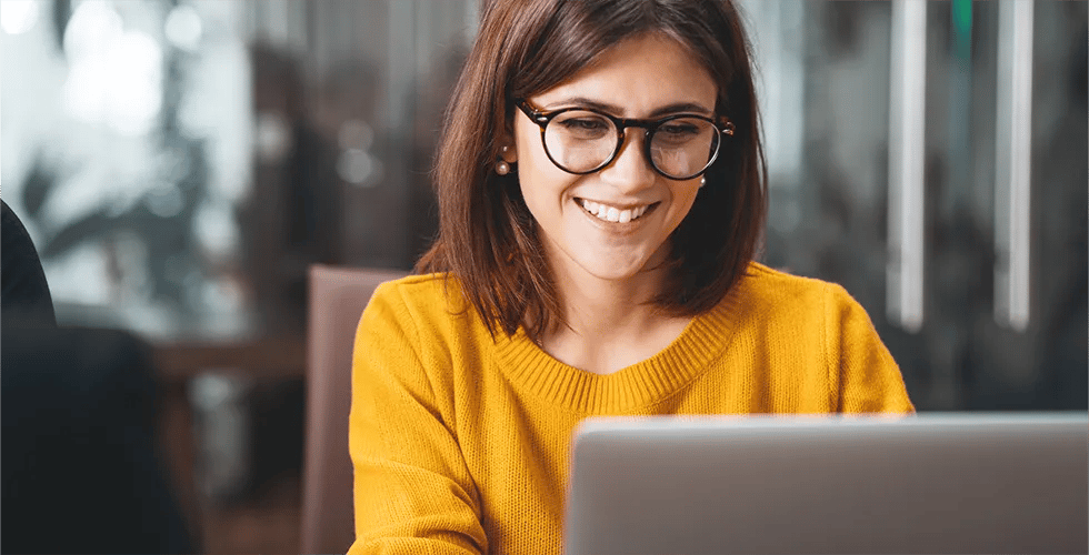 A young woman looks at a laptop and is happy about the translation of her website