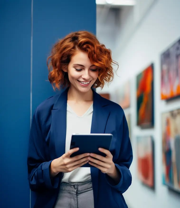 Eine junge lächelnde Frau in einer Kunstgallerie liest auf ihrem iPad ihre Kunst- und Kultur-Übersetzung