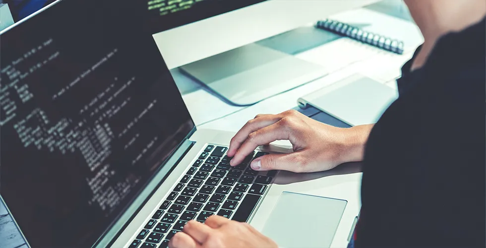 Ein IT-Experte sitzt am Laptop programmiert den Coder der API.