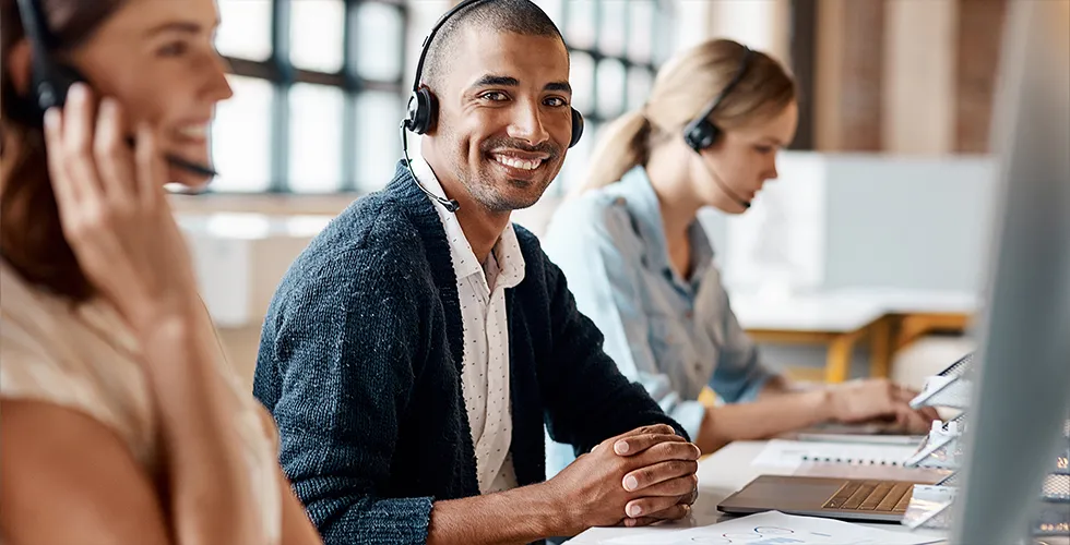 A service employee with a headset looks into the camera and smiles.