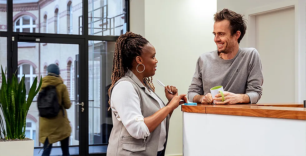 Two colleagues chat at the reception desk in tolingo's Hamburg office. 