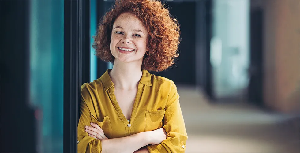A professional translator leans against the wall and smiles into the camera.