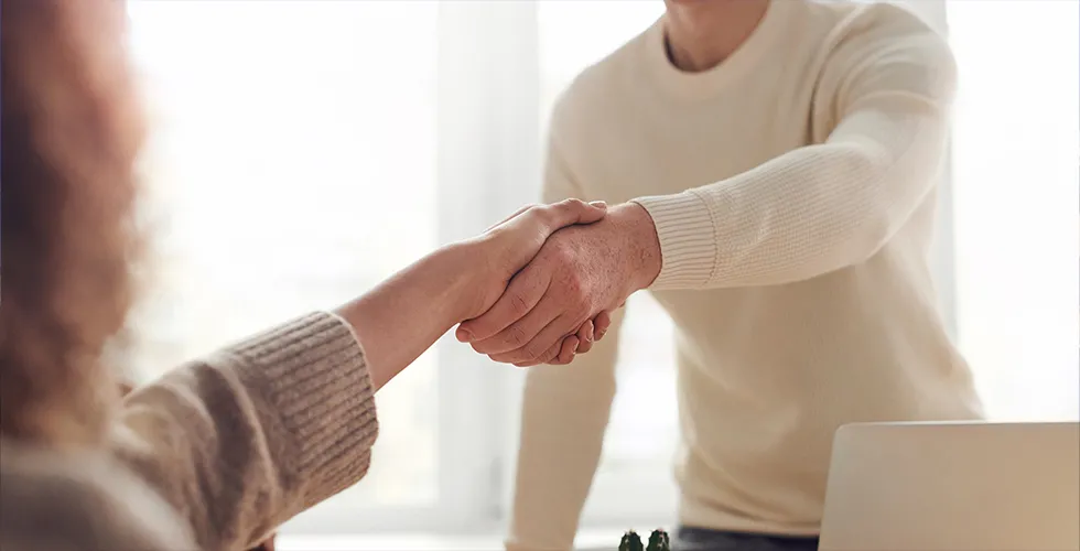Eine Frau und ein Mann geben sich die Hand auf die guten Geschäfte.