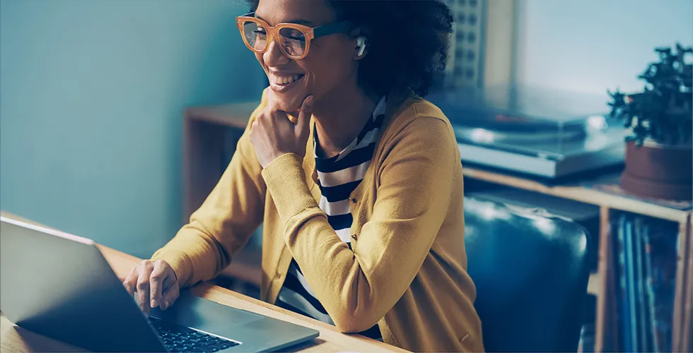 A young woman sits in front of her laptop and is happy about the result of her specialist translation.
