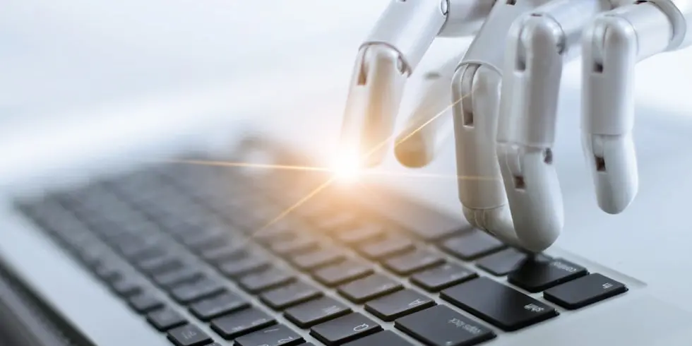 Roboterhand tippt auf Laptop: Korrektorat von KI-Texten
