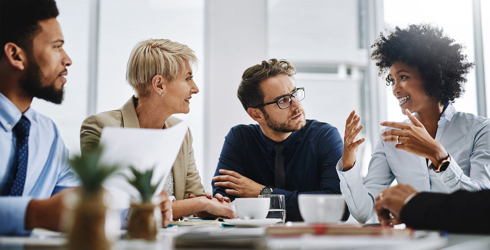 Vier Kolleg:innen, die sich am Arbeitsplatz erfolgreich auf Business Englisch unterhalten